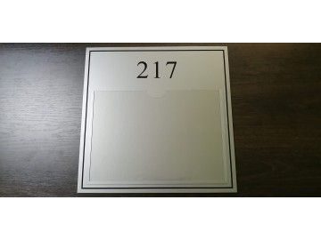 Одна табличка кабинета «217» крупно фронтально, на тёмной деревянной столешнице — кабинетные таблички Уфа — НеоШтамп